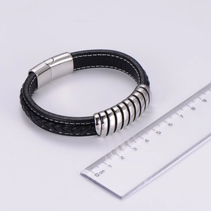 Detail view of black woven leather bracelet with magnetic clasp next to a scale ruler
