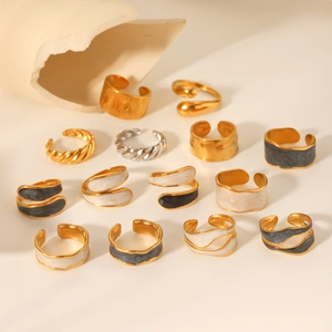 Artistic detail of gold and silver irregular enamel rings on a minimalist stone surface