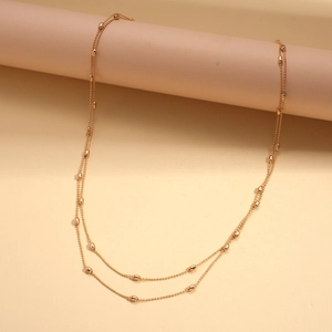 Detail of a layered golden beaded necklace with oval rice-shaped beads on fine chains