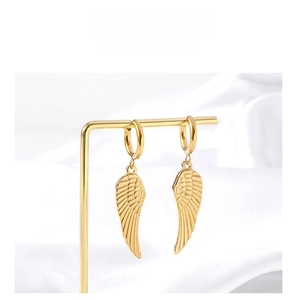 Gros plan de boucles d'oreilles ailes dorées avec plumes sur un support de luxe