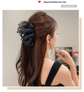 Détail de la pince à cheveux en dentelle noire à pois blancs sur les cheveux