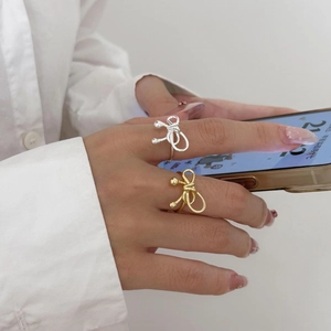 Detail of hand wearing layered gold and silver wire bow rings with spherical accents