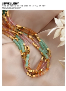Close-up of handmade multilayer beaded necklace with colorful stones on champagne silk