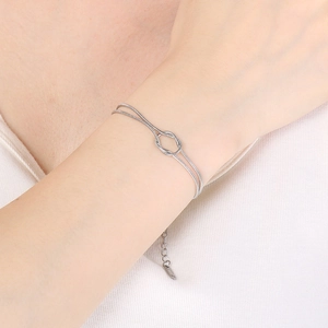 Detail of silver double-layered snake chain bracelet with center knot design