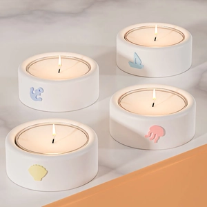 Dettaglio di quattro portacandele in ceramica con motivi marini su piano in marmo