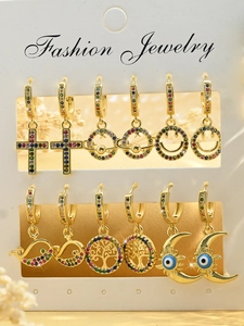 Close-up of 6 pairs of gold earrings with colorful zircon crosses and evil eye charms