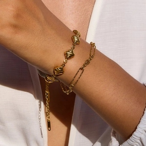 Goldenes Büroklammern- und Croissant-Armband-Set am Handgelenk mit sanftem natürlichem Licht