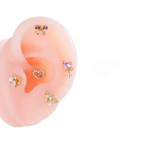Detail showing five gold-plated cartilage studs with butterfly and heart-shaped crystals