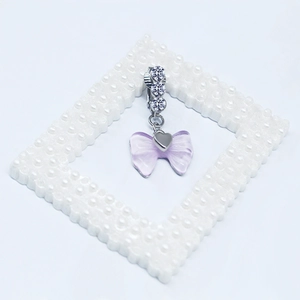 Détail d'un pendentif cœur argenté avec nœud violet et pierres en zircon brillant