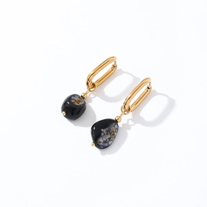 Detailed view of irregular black natural stone pendants with elegant gold metal hoop earrings