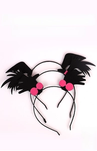 Close-up of black felt bat wings on Halloween headbands with pink pom-pom details