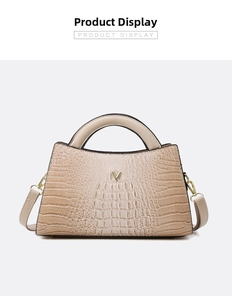 Detail view of beige crocodile embossed handbag with golden V-shaped metal logo and straps