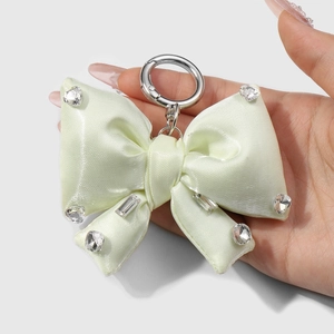 Pale green satin bow keychain with sparkling rhinestones and silver ring held in hand