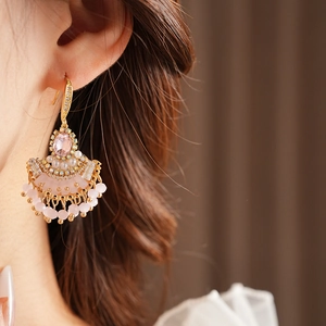 Détail de boucles d'oreilles vintage en forme d'éventail doré avec cristaux roses et glands