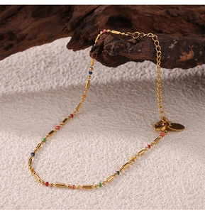 Close-up of golden titanium necklace with colorful beads on a natural wood surface