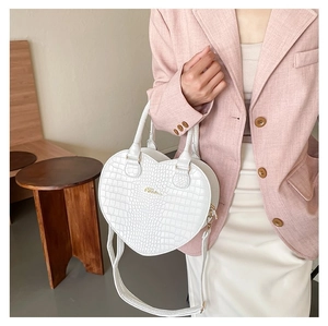 Détail du sac à main blanc en forme de cœur avec motif crocodile et logo Clara doré