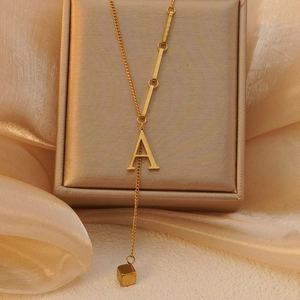 Elegante gouden titanium stalen Y-vormige ketting met letter A hanger op zijden achtergrond