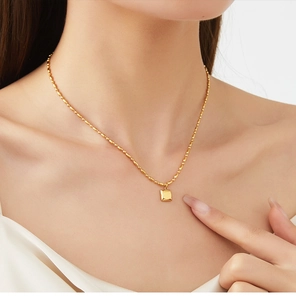 Gros plan d'un modèle portant un collier en acier doré 18K avec pendentif carré chic