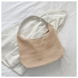 Close-up of beige woven shoulder bag with white wide strap on fabric background