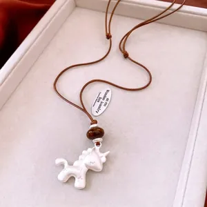 Collier licorne minimaliste avec cordon réglable marron sur un support en velours
