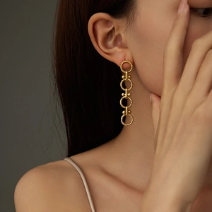 Detail of gold geometric earrings with four textured linked rings on a model