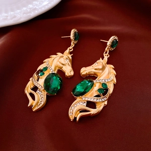 Détail de boucles d'oreilles tête de cheval dorées rétro avec pierres vertes et zircons