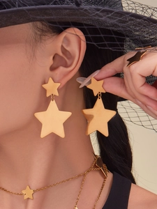 Detailed view of model wearing golden star jewelry set including earrings, ring and necklace