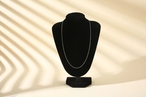 Detail of elegant silver metal chain necklace displayed on a black mannequin stand