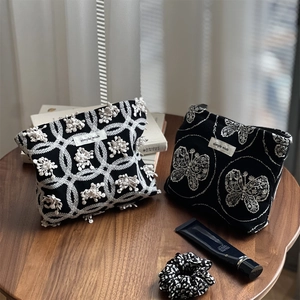 Close-up of black canvas makeup bags with butterfly embroidery and lace flower details