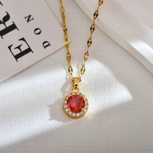 Macro shot of gold leaf chain necklace with red gemstone sunflower pendant and diamonds