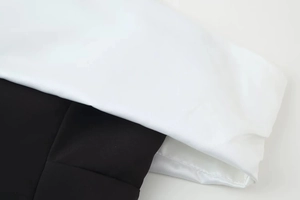 Detailed view of the sharp black and white contrast stitching on a bow knot dress