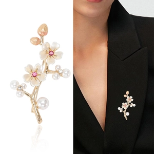 Elegant gold plum branch brooch with white flowers and pearls on black suit lapel