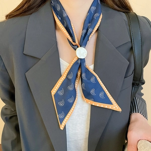 Detail of silk scarf with paisley pattern and white round ring buckle on neck