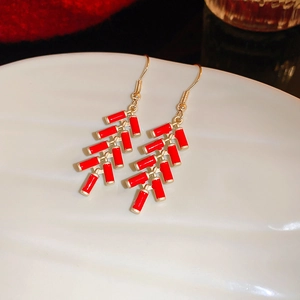 Close-up of red firecracker drop earrings with golden hooks in traditional style
