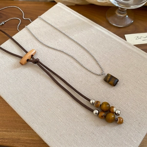 Detail of vintage ethnic style tiger eye pendant necklaces on minimalist book background