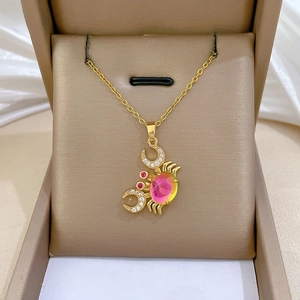 Macro view of gold crab pendant featuring large pink gemstone and sparkling zircon moon
