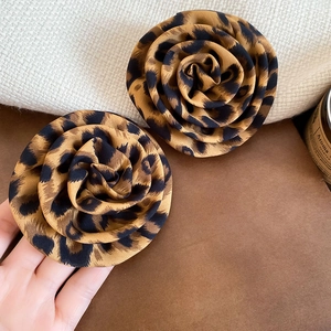 Detail showing handmade leopard print fabric rose earrings with soft textile texture