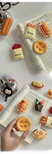 Detailed view of 3D food fridge magnets like baguette and tart on vintage paper