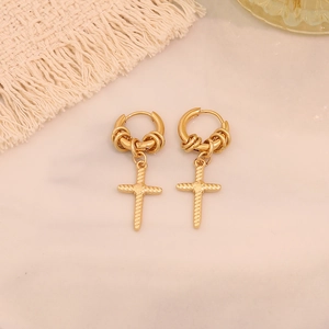 Detailed view of gold hoop earrings featuring cross pendants on marble background