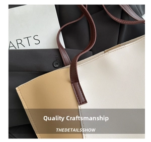 Detail of color-block tote bag with brown straps and textured synthetic leather finish