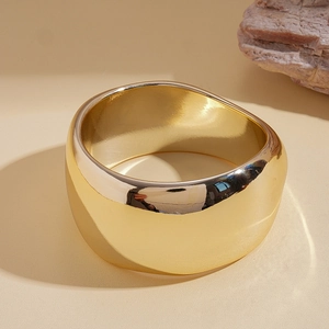 Close-up of a wide polished gold dome ring showing minimalist texture and metallic luster