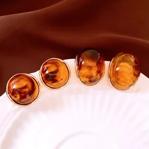 Retro amber caramel round and oval earrings with gold trim on a white porcelain plate