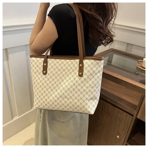 Detail view of large retro tote bag with brown leather handles worn over the shoulder
