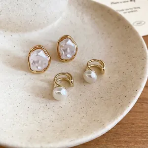 French vintage irregular pearl ear clips set in a gold finish on a beige ceramic tray