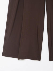 Dettaglio ravvicinato dei pantaloni larghi marrone scuro con cuciture precise sull'orlo