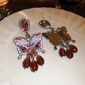 Detail of pink butterfly earrings with sparkling crystals and red teardrop pendants