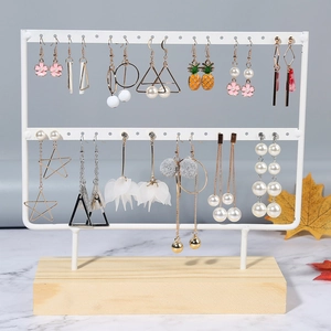 Detailed view of white metal jewelry rack with various earrings on a wooden base