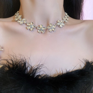 Detail of silver floral necklace with sparkling crystals worn by a model on a dark dress