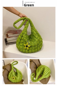 Detail view of grass green quilted puffer tote bag with decorative yellow flower pendant