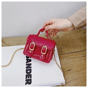 Macro detail of fuchsia patent leather satchel bag with glossy finish and gold metal chain